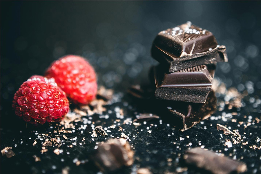 Blocks of Chocolates Next to Raspberries