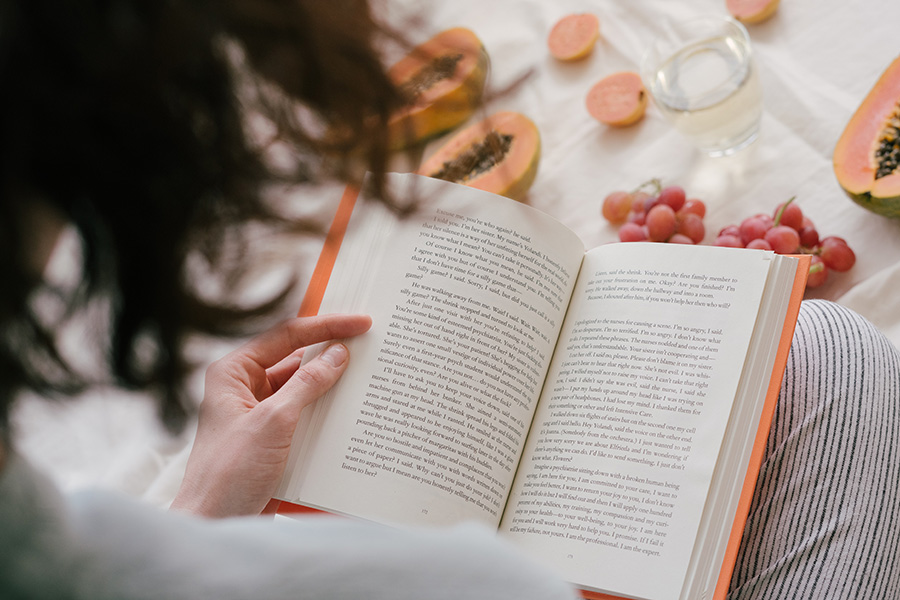 Person Reading a Book Eating Fruit